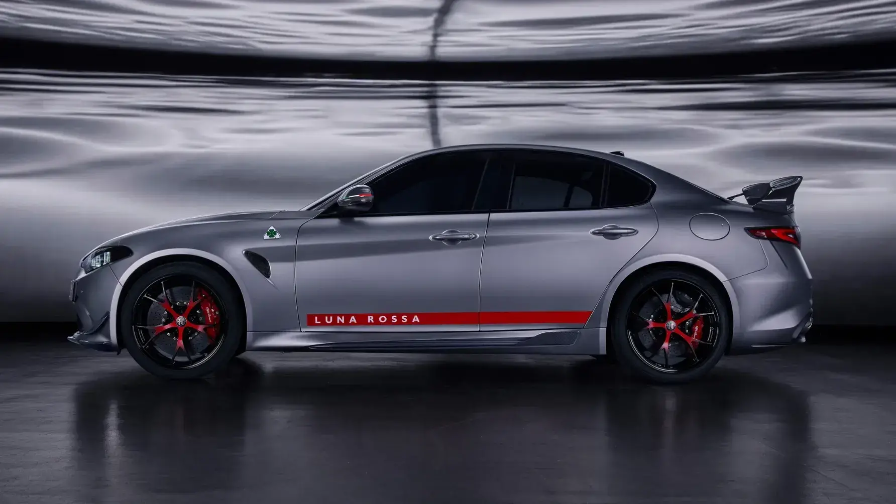 Alfa Romeo Giulia Luna Rossa rear three-quarter view showcasing massive carbon fiber wing and quad exhaust pipes