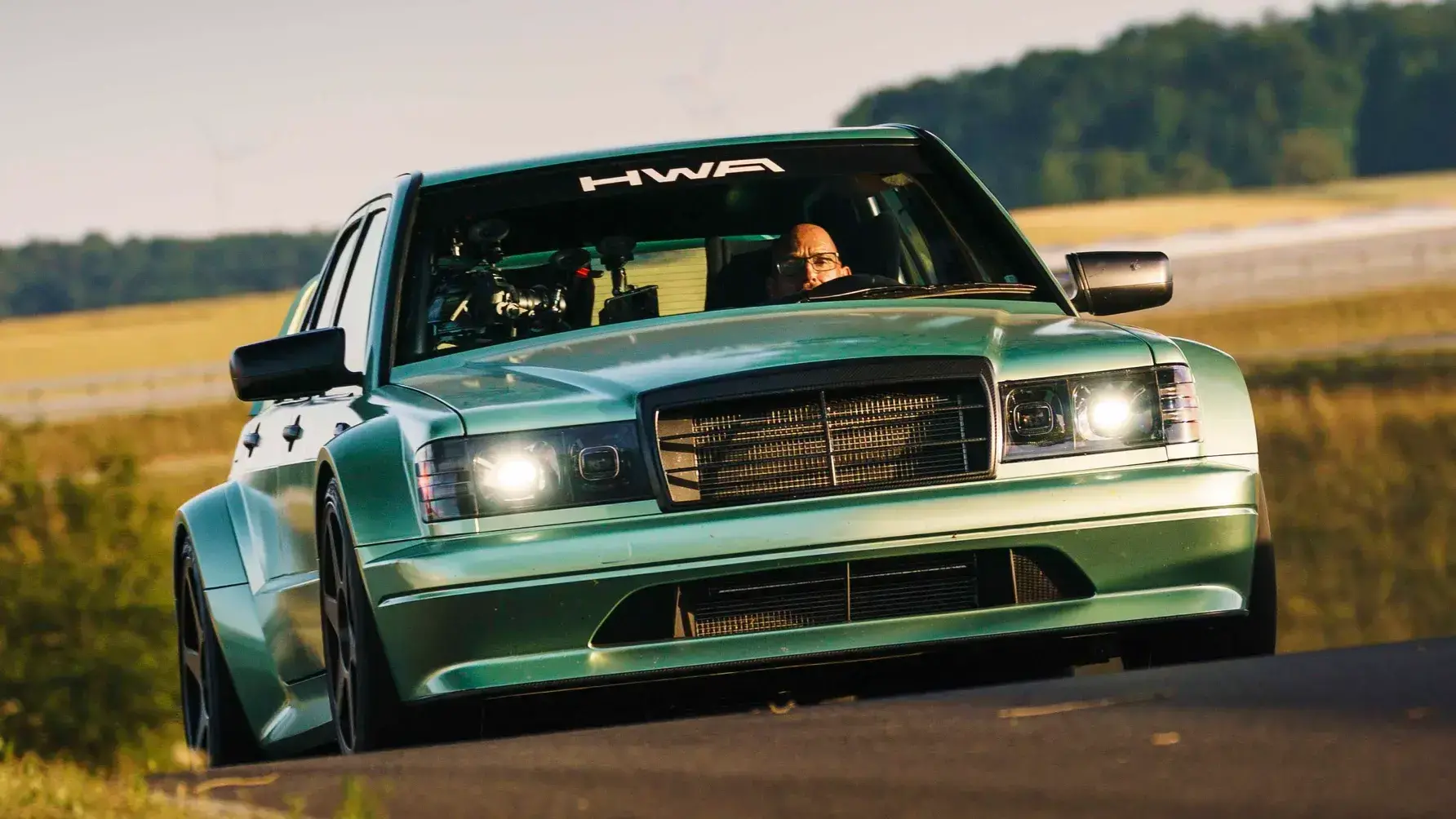 HWA Evo II Restomod Track Testing at Boxberg with Iconic Rear Wing HWA Mercedes 190E Evo II restomod on track showcasing aggressive DTM-inspired aerodynamics and wide stance