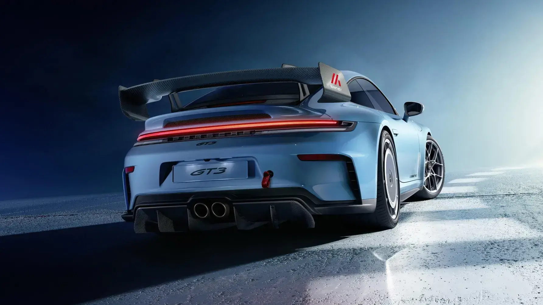 Manthey Porsche 911 GT3 992.2 rear view showing swan-neck wing with gurney and carbon wheel covers