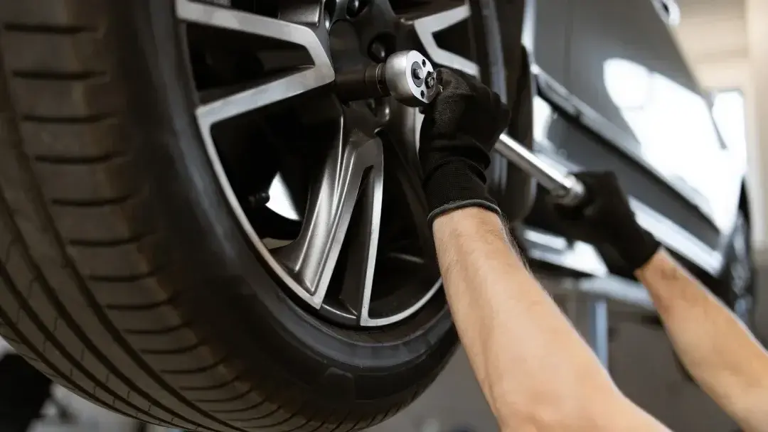 Professional technician performing roadside tire change service with safety equipment and tools on highway shoulder