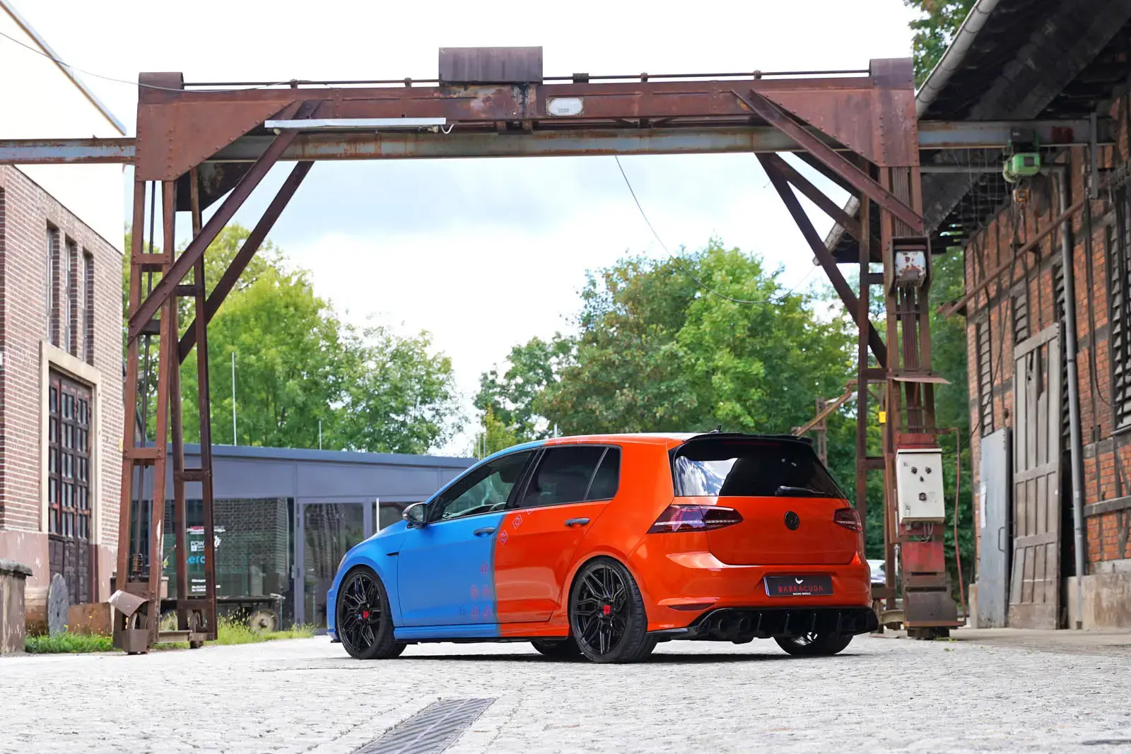 Rear view of MB-Customs Volkswagen Golf R with red wrap, Rieger diffuser, and Remus exhaust tips